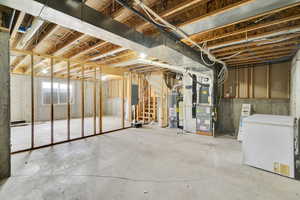 Basement featuring electric panel, heating unit, water heater, and fridge