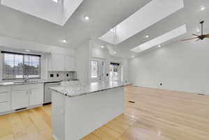 Kitchen with white cabinets, a kitchen island, light hardwood / wood-style flooring, dishwasher, and sink