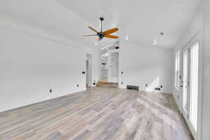 Unfurnished living room featuring light hardwood / wood-style flooring, vaulted ceiling, and ceiling fan