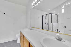 Bathroom featuring vanity, hardwood / wood-style floors, a shower with shower door, and toilet