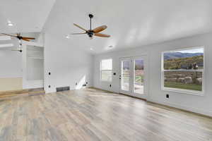 Unfurnished living room featuring a textured ceiling, lofted ceiling, and light wood-type flooring