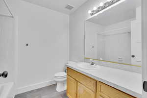 Full bathroom featuring vanity, hardwood / wood-style flooring, toilet, and tub / shower combination