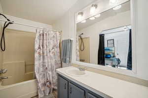 Bathroom featuring vanity, vaulted ceiling, and shower / tub combo