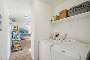 Laundry area with light hardwood / wood-style flooring and separate washer and dryer