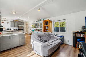 Living room featuring sink, light hardwood / wood-style flooring, and lofted ceiling with beams