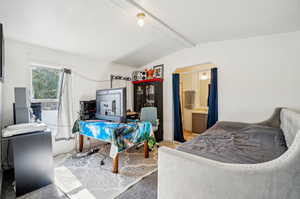 Interior space featuring connected bathroom and vaulted ceiling with beams