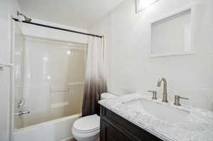 Full bathroom with toilet, shower / tub combo with curtain, and vanity