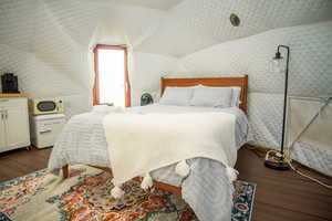 Bedroom with wood-type flooring and lofted ceiling