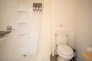 Bathroom with hardwood / wood-style floors, toilet, and walk in shower