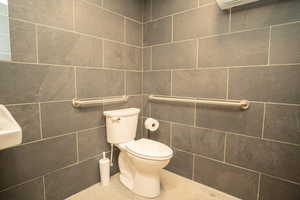 Bathroom with toilet and tile walls