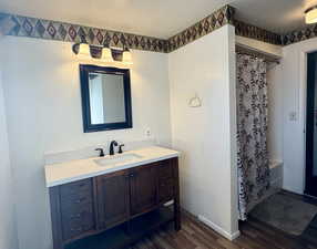 Bathroom with vanity, shower / bath combination with curtain, a textured ceiling, and hardwood / wood-style flooring