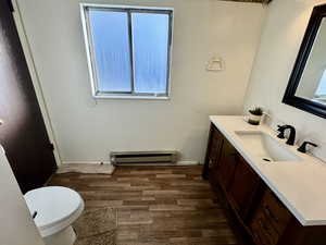 Bathroom with a wealth of natural light, vanity, baseboard heating, and hardwood / wood-style floors