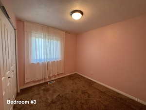 Carpeted empty room featuring a textured ceiling