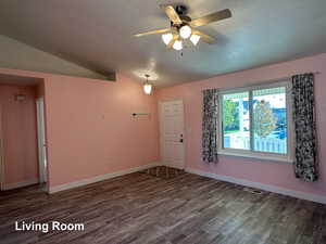 Spare room with dark wood-type flooring, ceiling fan, a textured ceiling, and lofted ceiling