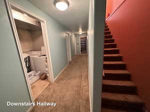 Hall featuring washing machine and dryer, a textured ceiling, and carpet