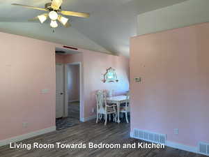 Unfurnished dining area featuring dark wood-type flooring, ceiling fan, and lofted ceiling