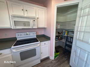 Kitchen featuring white cabinetry, white appliances, and dark hardwood / wood-style floors