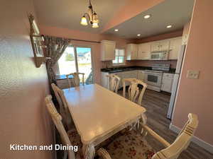 Dining room featuring dark hardwood / wood-style flooring, sink, lofted ceiling, and an inviting chandelier