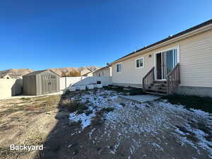 Snow covered property featuring a mountain view and a storage shed