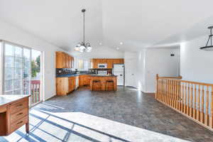 Kitchen with lofted ceiling, white appliances, decorative light fixtures, and a kitchen island