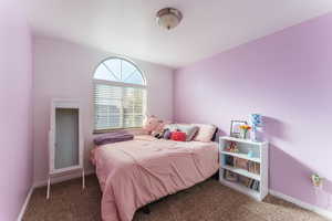 Bedroom with vaulted ceiling and carpet floors