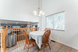 Tiled dining area featuring a chandelier and a high ceiling