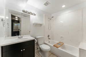 Full bathroom featuring  shower combination, a textured ceiling, toilet, vanity, and tile patterned flooring