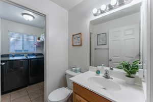 Bathroom with vanity, washer and clothes dryer, toilet, and tile patterned flooring