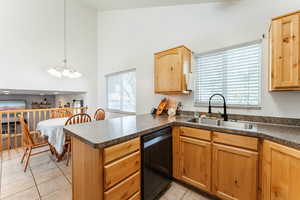 Kitchen featuring sink, dishwasher, kitchen peninsula, pendant lighting, and light tile patterned floors