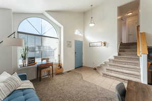 Carpeted entrance foyer featuring high vaulted ceiling and plenty of natural light