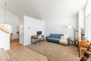 Home office featuring a notable chandelier, vaulted ceiling, light carpet, and a healthy amount of sunlight