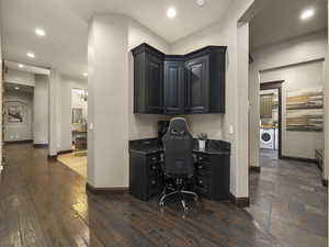 Office space featuring washer / dryer, built in desk, and dark hardwood / wood-style floors