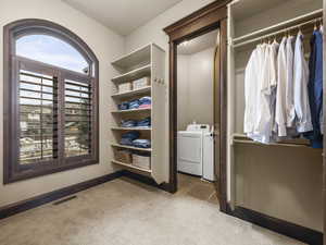 Walk in closet with washing machine and dryer and light colored carpet