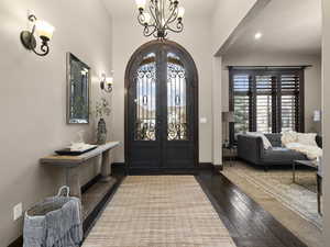 Entrance foyer featuring an inviting chandelier, french doors, and dark hardwood / wood-style floors