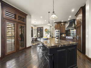 Kitchen featuring a spacious island, dark hardwood / wood-style flooring, custom exhaust hood, and hanging light fixtures