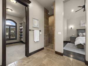 Bathroom featuring a tile shower, ceiling fan, and a textured ceiling