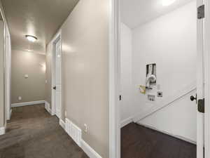 Hall featuring a textured ceiling and dark hardwood / wood-style floors