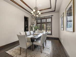 Dining room featuring a notable chandelier, dark hardwood / wood-style floors, and a raised ceiling