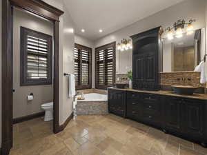 Bathroom featuring toilet, a relaxing tiled tub, and vanity