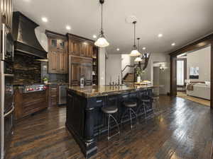 Kitchen featuring custom exhaust hood, stainless steel appliances, dark wood-type flooring, and a large island