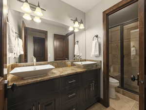 Bathroom featuring vanity, tile patterned flooring, toilet, and an enclosed shower