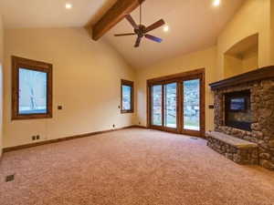 Unfurnished living room with beam ceiling, carpet floors, high vaulted ceiling, and ceiling fan