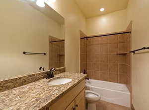 Full bathroom with tiled shower / bath, vanity, toilet, and tile patterned flooring