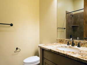 Bathroom with vanity, tiled shower, and toilet