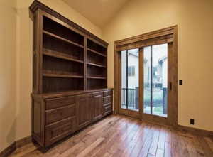 Doorway with light hardwood / wood-style floors, lofted ceiling, and a healthy amount of sunlight