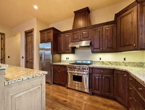 Kitchen with light stone countertops, stainless steel appliances, and light wood-type flooring