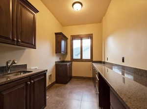 Kitchen featuring tile patterned flooring, dark brown cabinets, sink, and dark stone counters