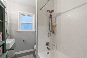 Bathroom with toilet, tiled shower / bath combo, and a textured ceiling