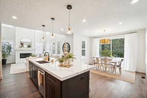 Kitchen with a large fireplace, sink, decorative light fixtures, a textured ceiling, and dark hardwood / wood-style flooring