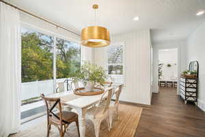 Dining space with dark hardwood / wood-style floors, a textured ceiling, and plenty of natural light